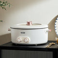 White electric pot with pink accents on a black cabinet against a beige wall.