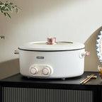 White electric pot with pink accents on a black cabinet against a beige wall.